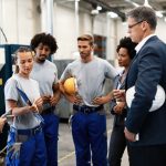 Female worker showing production reports to company managers in a factory.